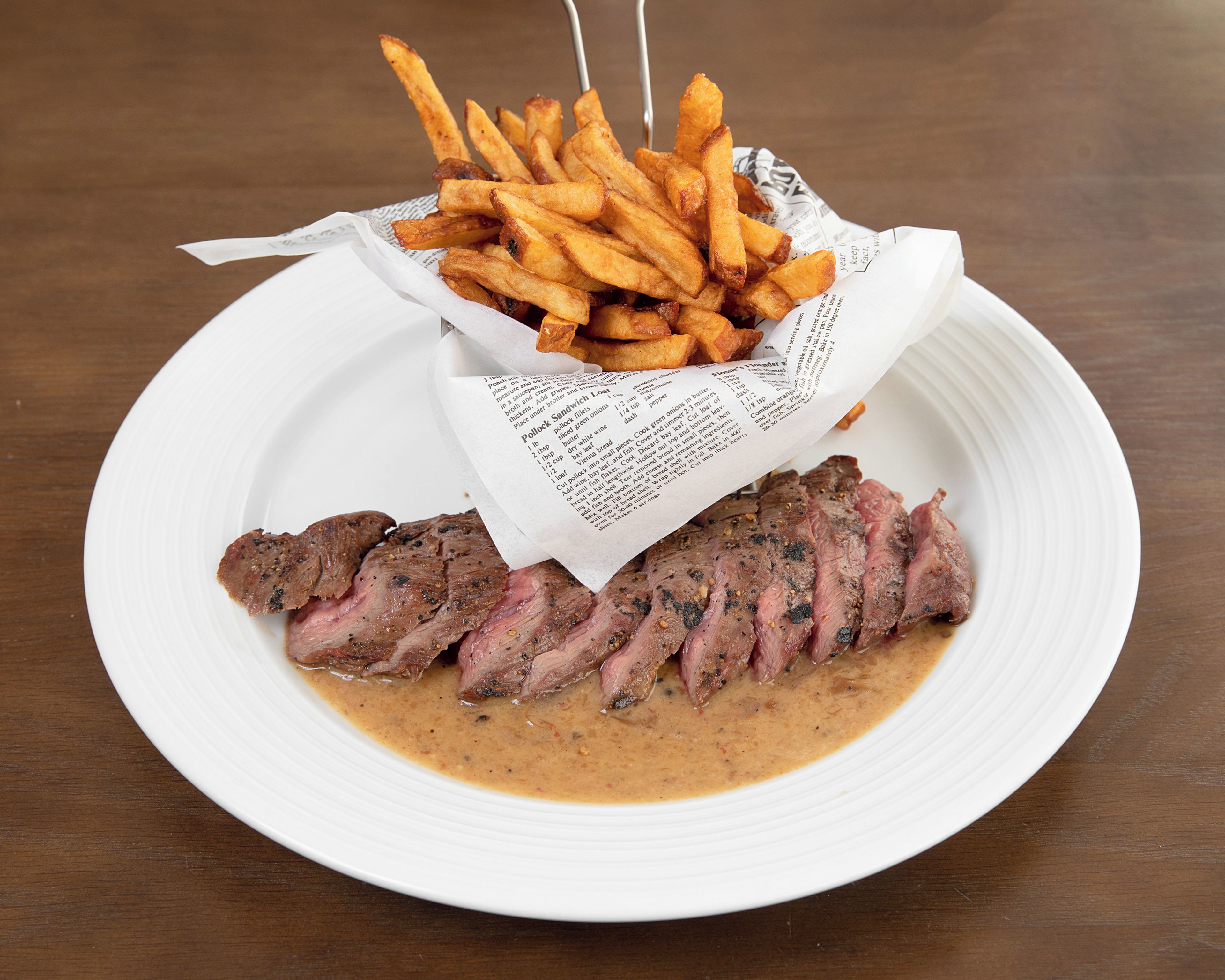 Een bord met plakjes vlees en een portie friet.