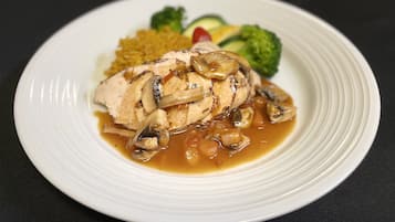 A plate with grilled chicken, mushrooms, and vegetables on a white plate.