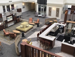 A spacious hotel lobby with a seating area, a bar, and a view of the hallway. - Holiday Inn Montreal Longueuil by IHG (Longueuil)