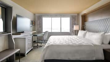 A hotel room with a bed, desk, chair, television, and a window.