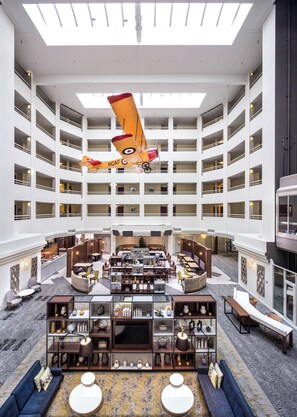 A multi-level hotel lobby with a central seating area, multiple floors, and a large windowed ceiling. - Holiday Inn Montreal Longueuil by IHG (Longueuil)