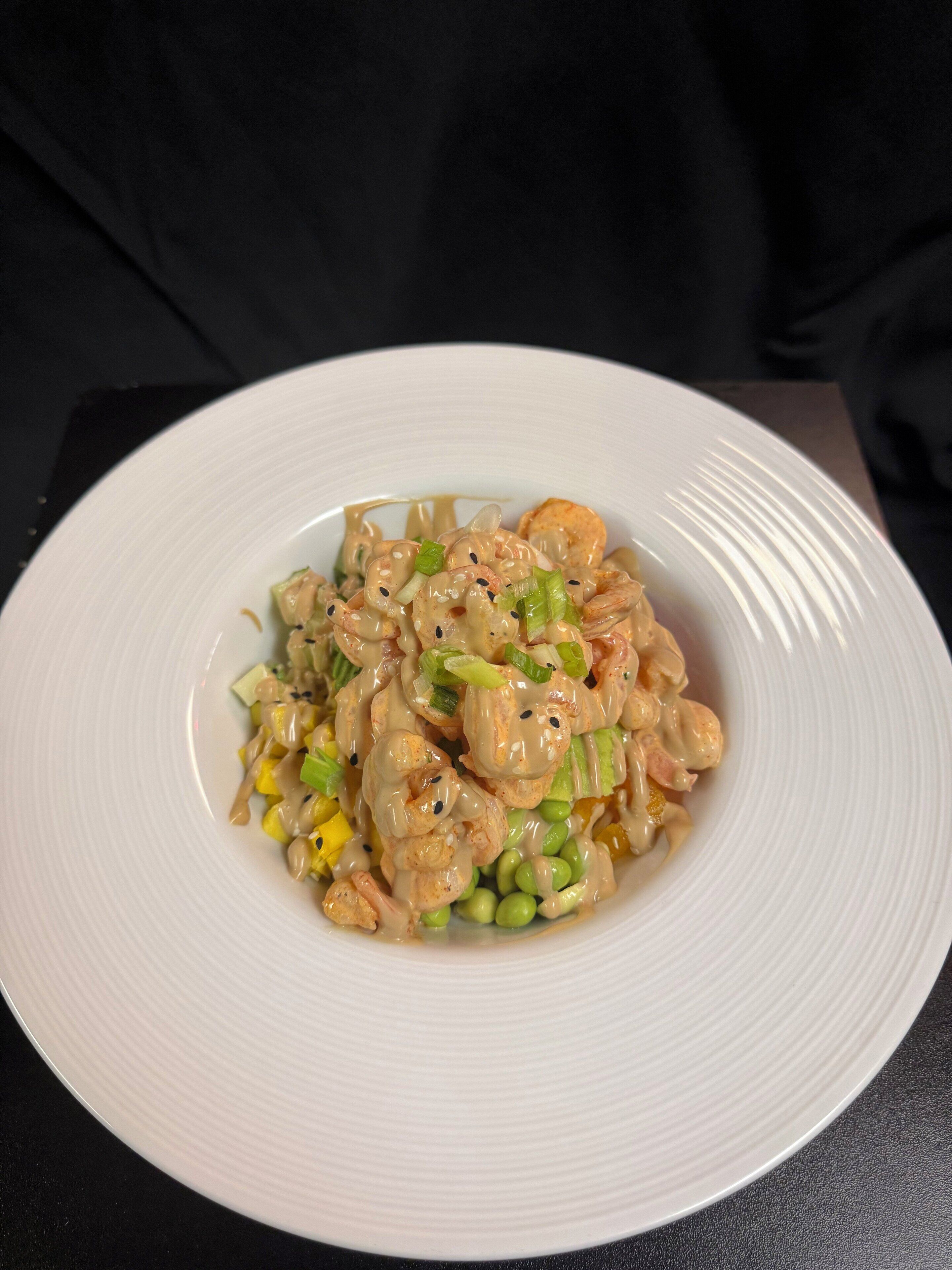 Un plato de camarones salteados con verduras y salsa sobre un plato blanco.