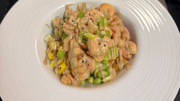 A plate of stir-fried shrimp with vegetables and sauce on a white plate.