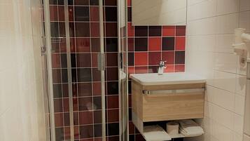 Une salle de bain moderne avec une douche à parois de verre, un meuble-lavabo en bois et un pare-feu en carreaux.