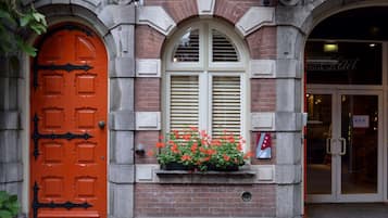 A red door with a window above it, a brick wall, and a sign for a hotel.
