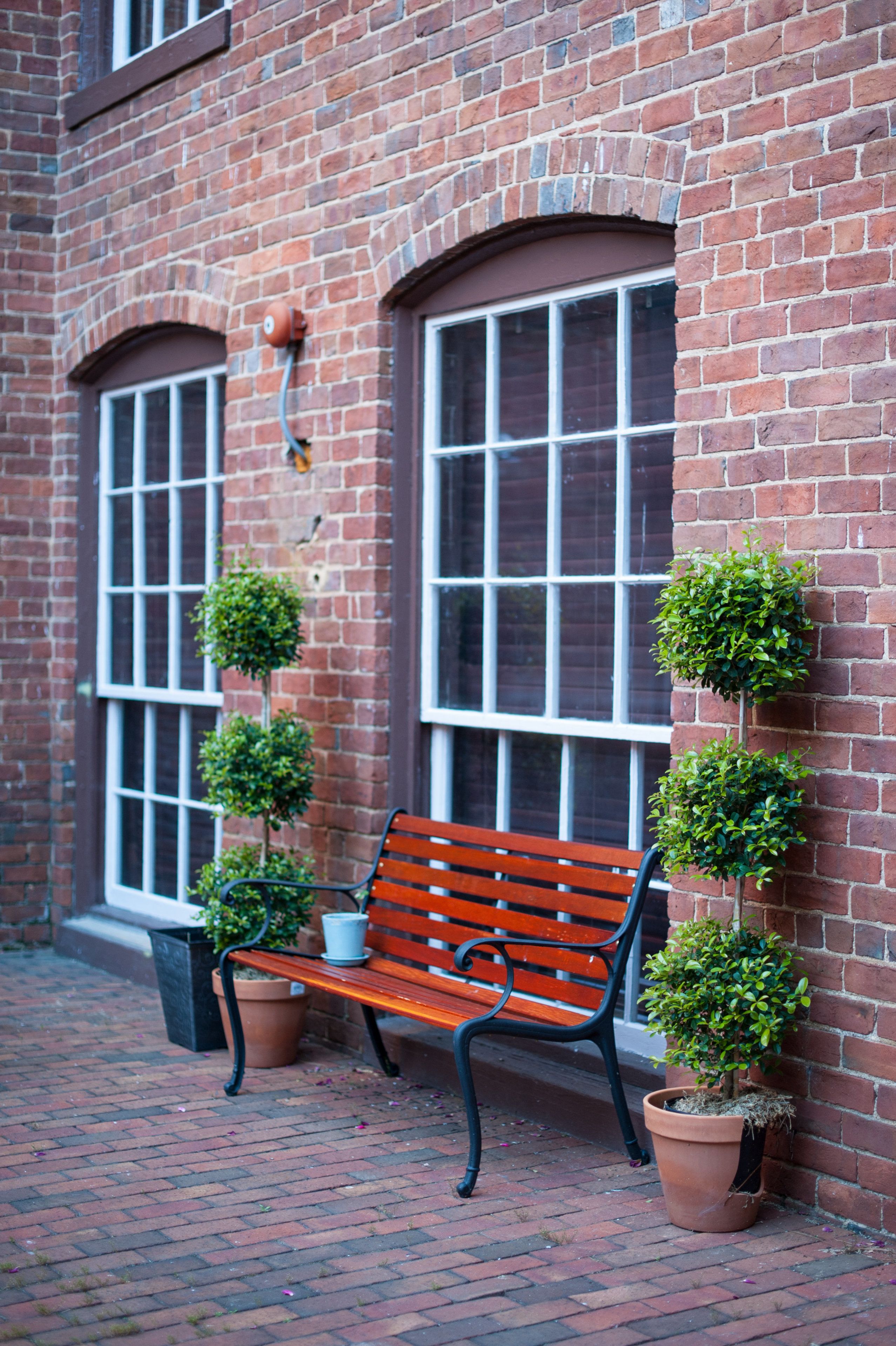 A brick building with two windows and a bench in front.