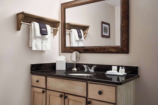 A bathroom with a sink, mirror, towel rack, and wooden cabinets.