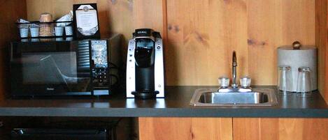 A kitchen with a microwave, coffee maker, and sink.