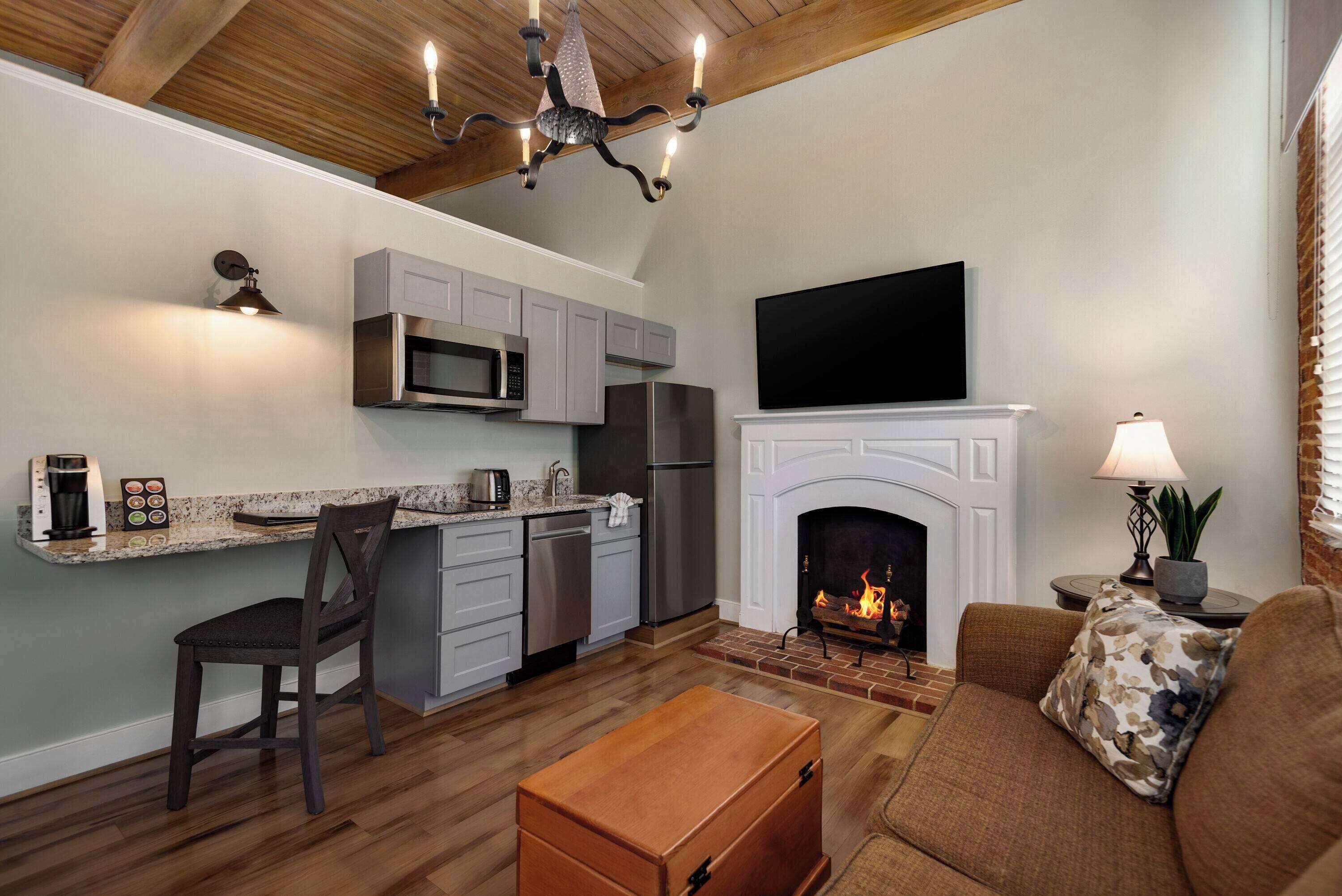 A modern kitchen with a built-in microwave, refrigerator, and a flat-screen TV above the fireplace.