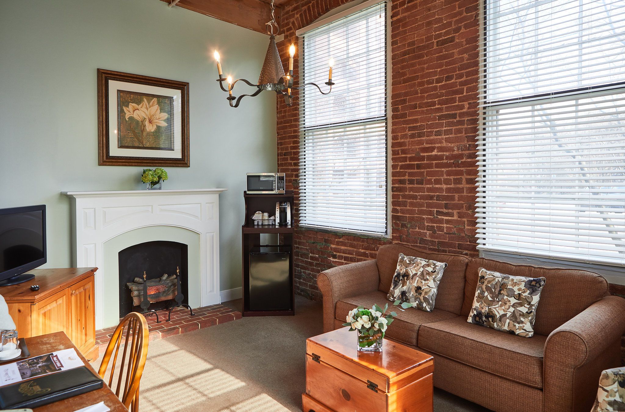 A living room with a fireplace, a sofa with patterned cushions, a wooden coffee table, and a television on a wooden cabinet.