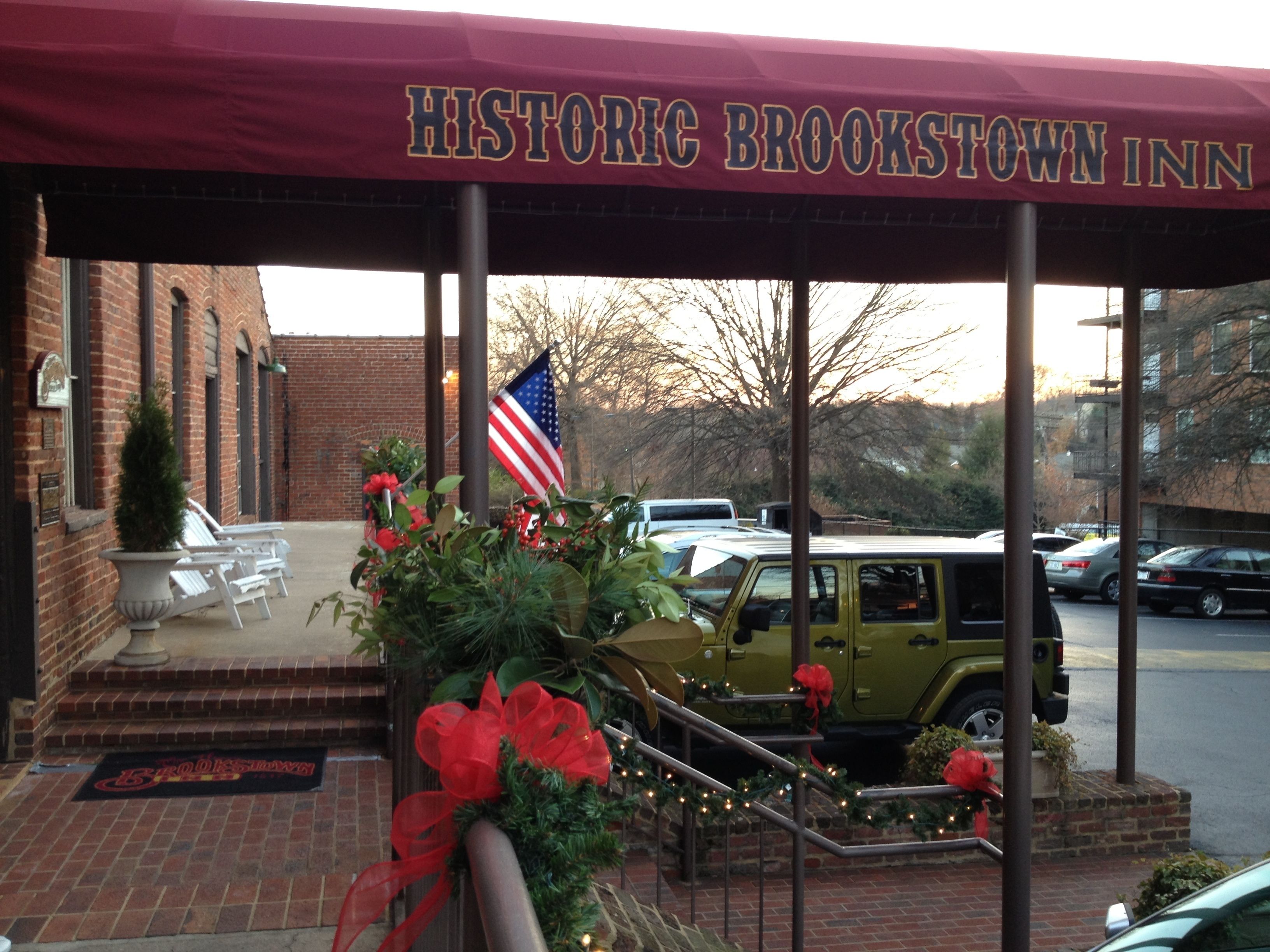The Historic Brookstown Inn entrance with a brick building, American flag, and a Jeep with a red bow.