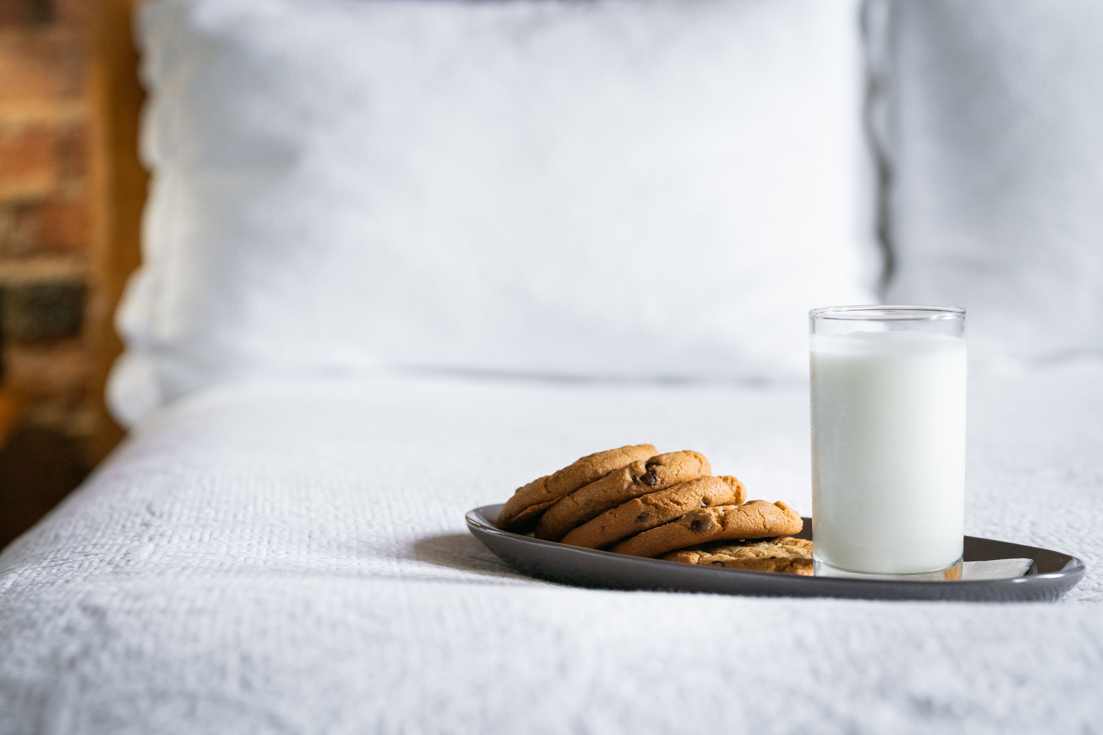 A plate of cookies and a glass of milk on a tray.