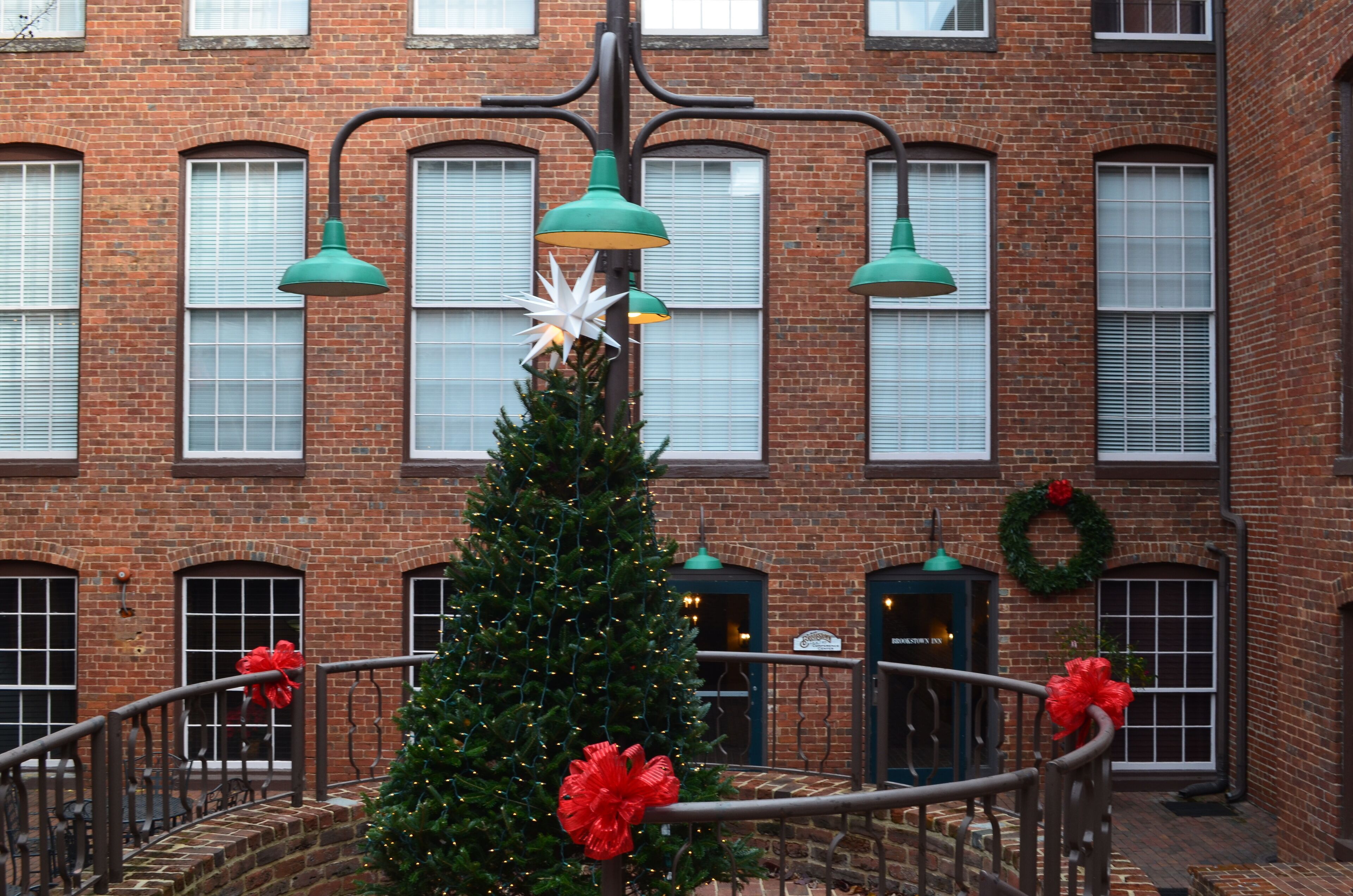 A brick building with a Christmas tree decorated with red bows and a white star.