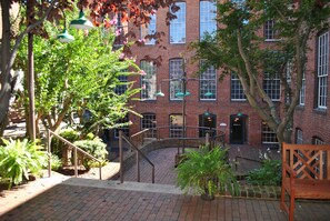 A courtyard with brick buildings, a staircase, and potted plants.