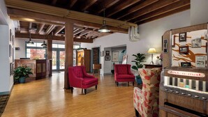 A spacious lobby with wooden floors, red armchairs, and a vintage refrigerator. - The Historic Brookstown Inn, Trademark Collection by Wyndham (Winston-Salem)