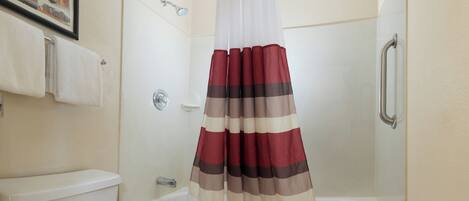 A bathroom with a shower curtain, a toilet, and a bathtub.