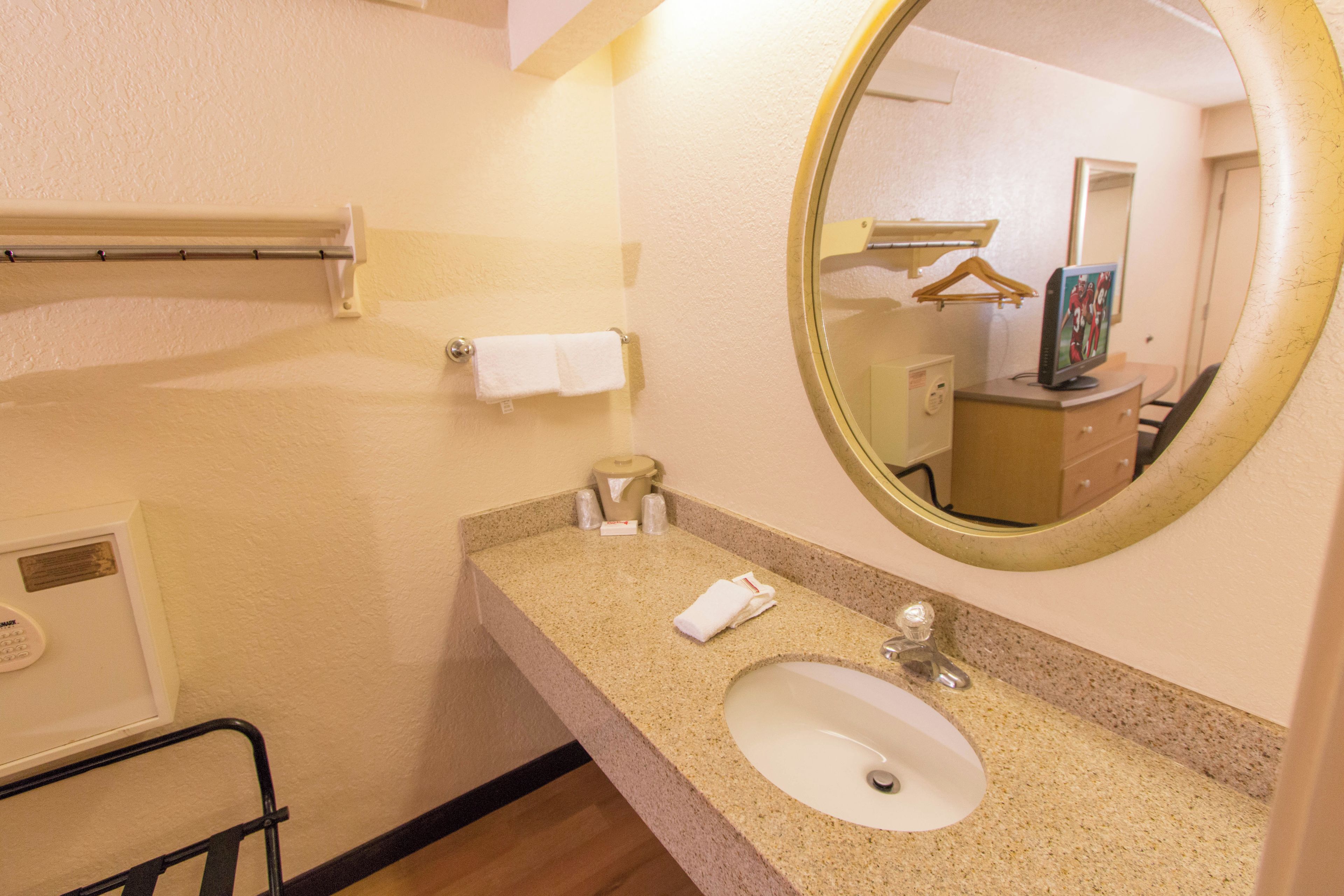 A bathroom with a sink, mirror, towel rack, and a small cabinet.