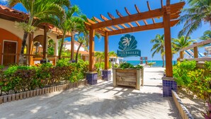 A beach entrance with a wooden pergola, palm trees, and a sign for SunBreeze Hotel. - Sunbreeze Hotel (San Pedro)
