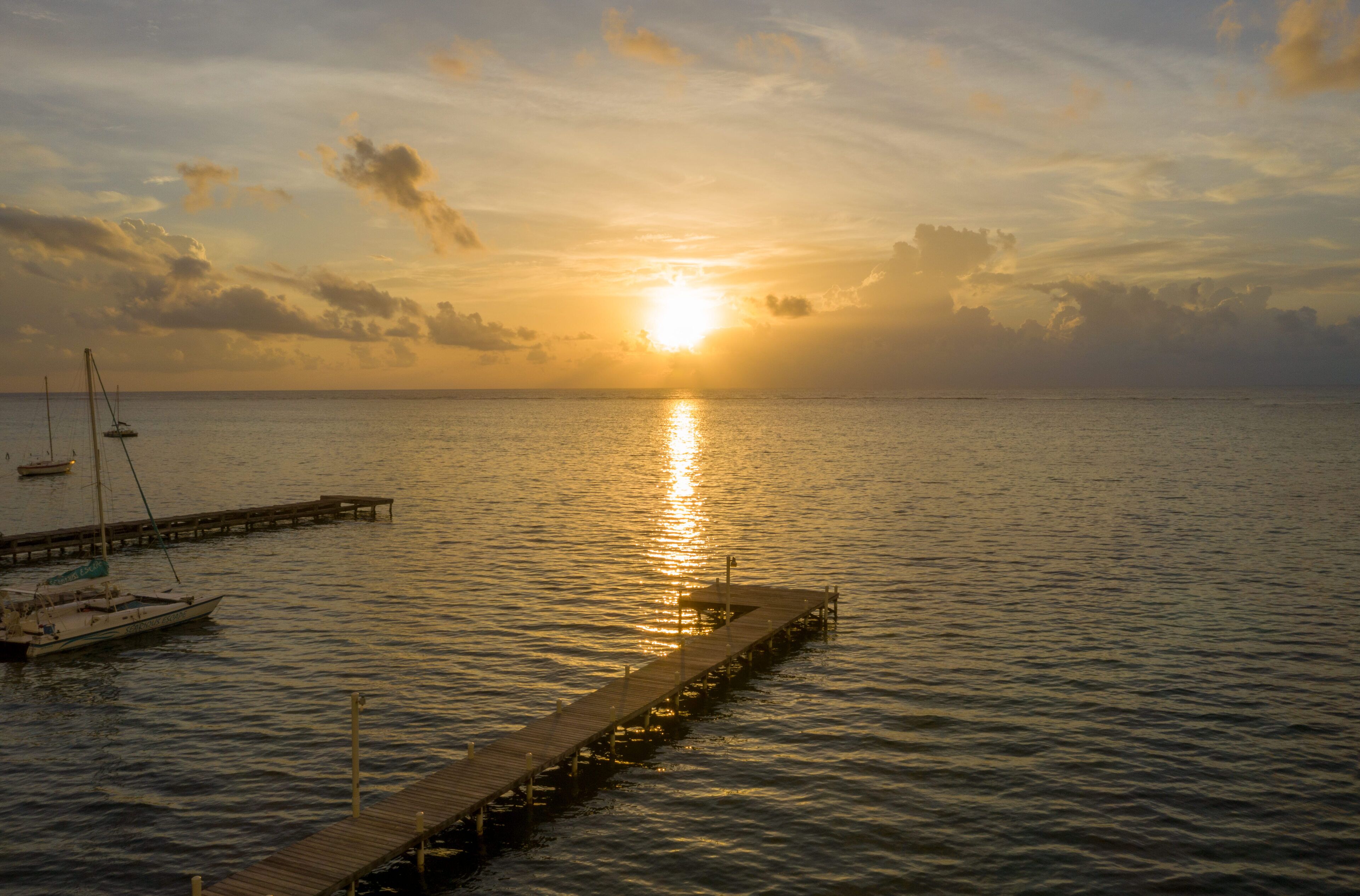 Un muelle se adentra en aguas tranquilas con un atardecer al fondo.