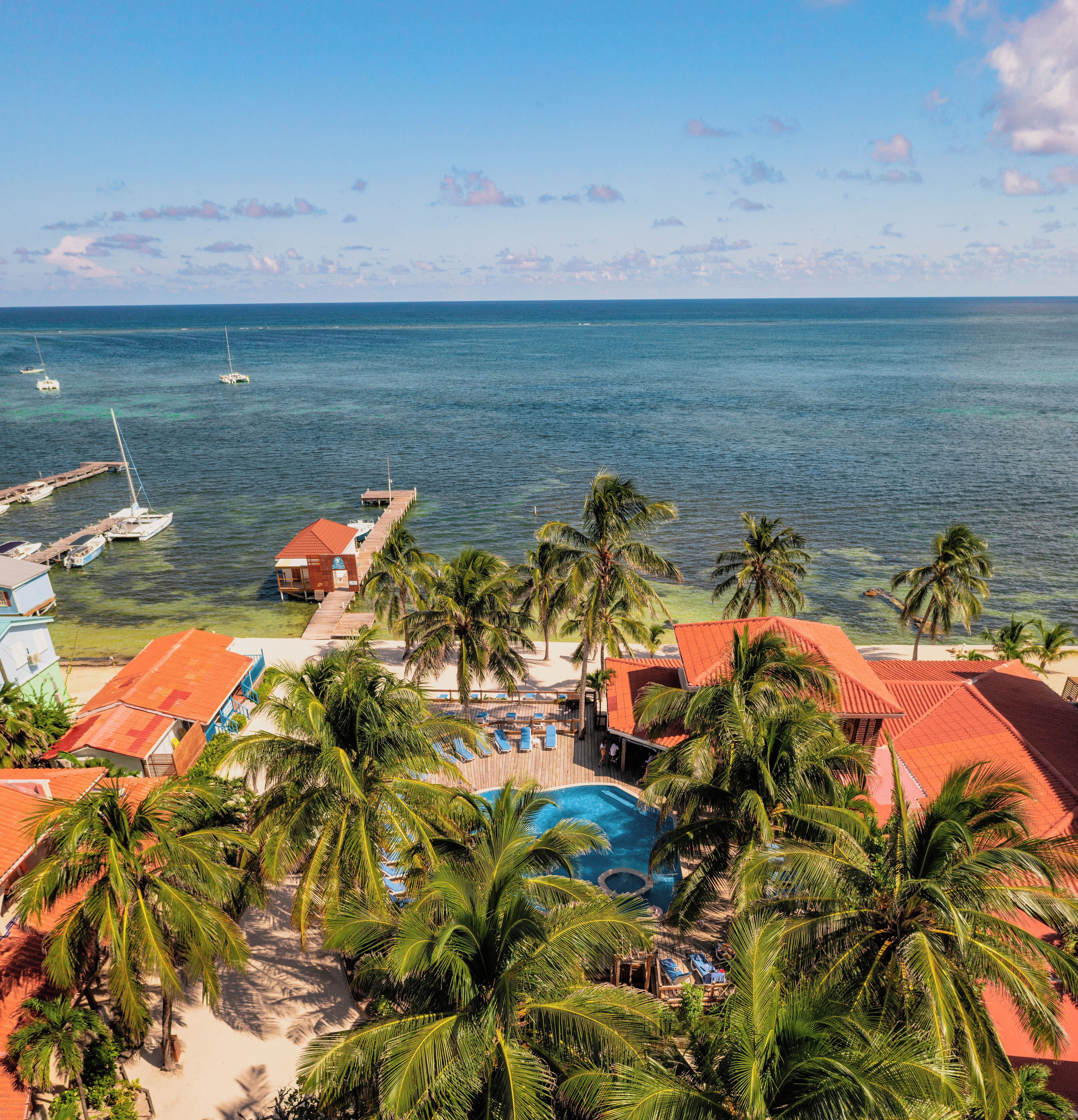 Ein Resort mit Swimmingpool, Palmen und Blick auf den Ozean.
