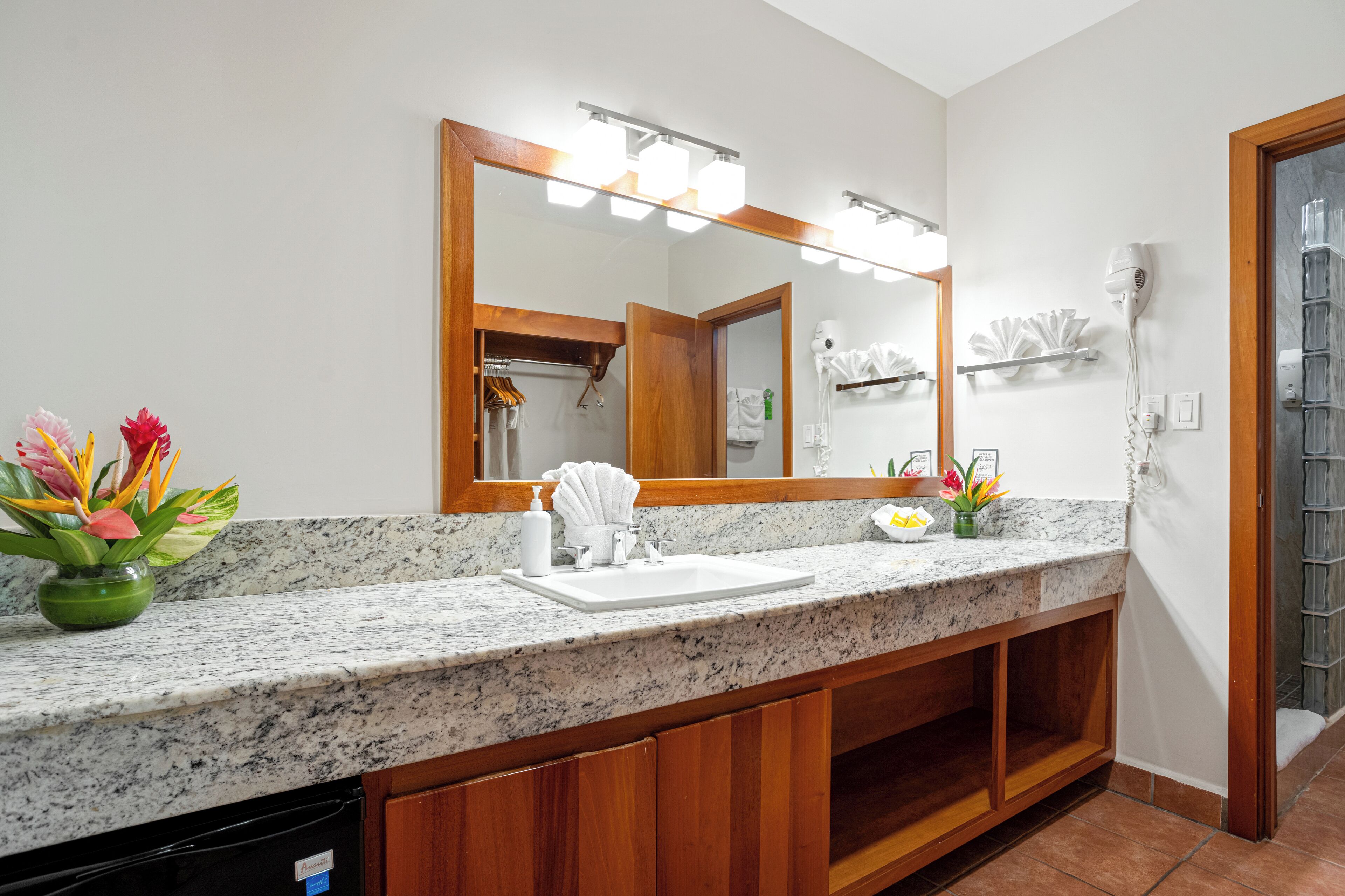 A bathroom with a granite countertop, a large mirror, a sink, and a towel rack.