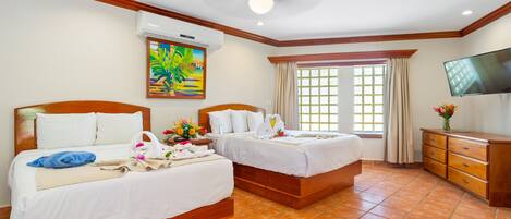 A hotel room with two beds, a TV, a painting, and a window with curtains.