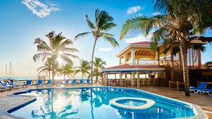 A pool with a wooden deck, lounge chairs, and palm trees. - Sunbreeze Hotel (San Pedro)