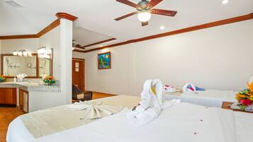 A hotel room with a bed, a desk, a chair, a bathroom, and a ceiling fan.