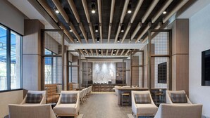 A spacious lobby with modern furniture, a central bar area, and large windows providing natural light. - Dallas/Addison Marriott Quorum by the Galleria (Dallas)