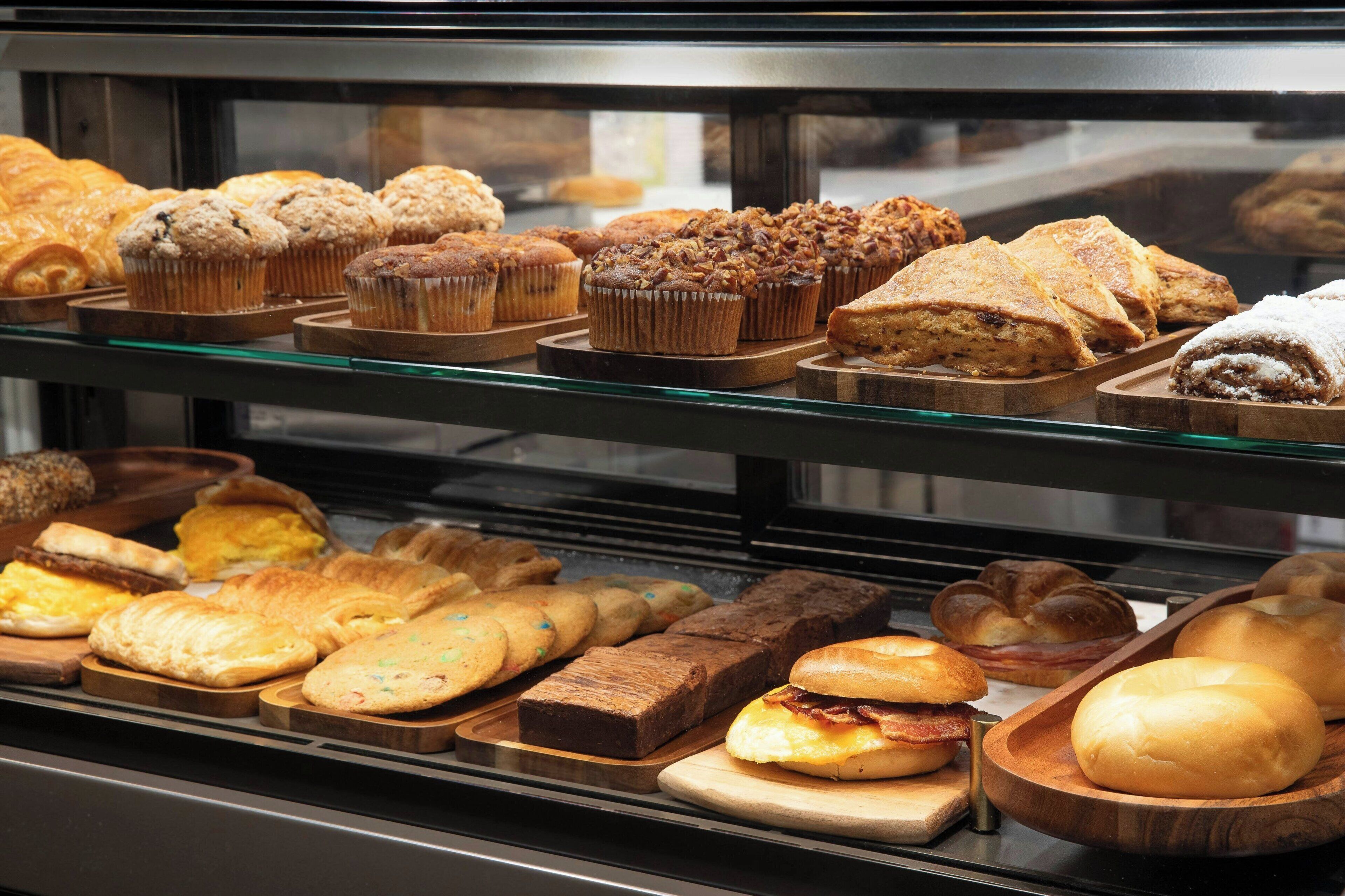 Un expositor de panadería con diversas opciones de productos horneados, como muffins, pasteles y pan.