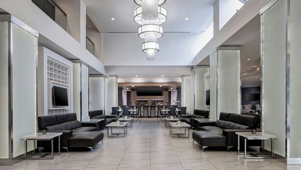 A spacious lobby with a modern chandelier, seating areas, and a bar. - Dallas/Addison Marriott Quorum by the Galleria (Dallas)