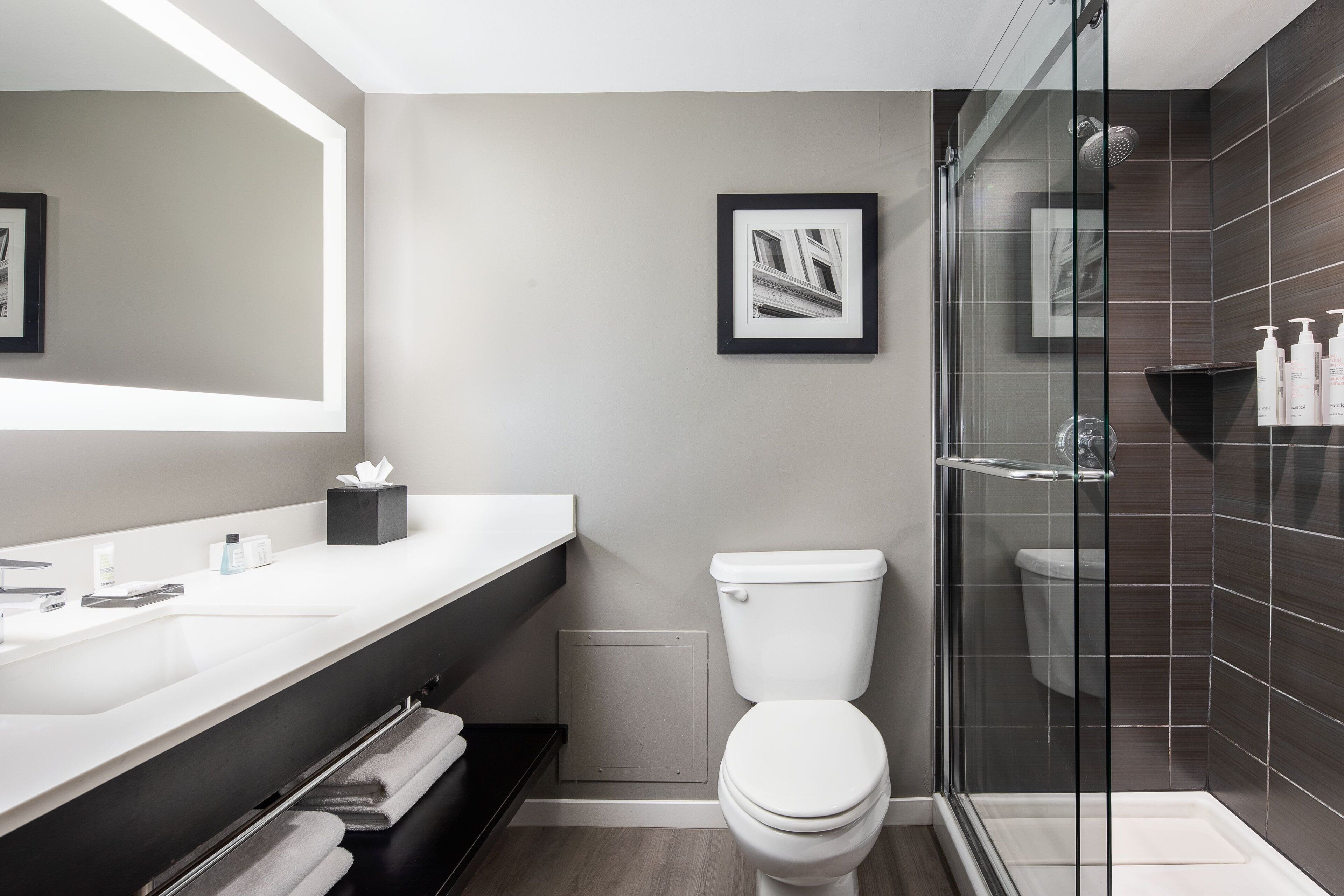 Un baño moderno con cabina de ducha de vidrio, inodoro blanco y tocador con espejo.