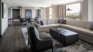 A modern living room with a sectional sofa, a coffee table, and a dining area with chairs and a small table. - Dallas/Addison Marriott Quorum by the Galleria (Dallas)