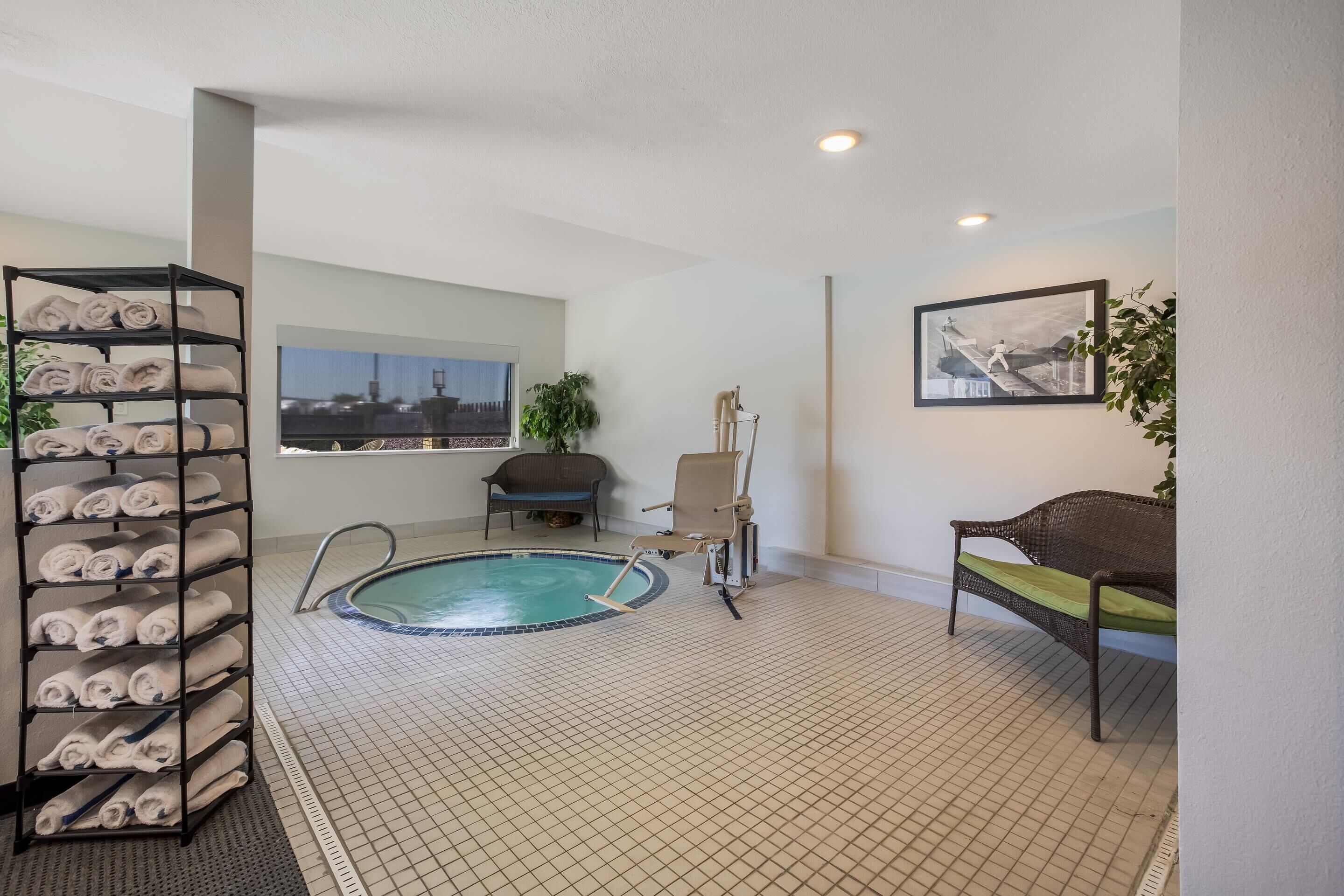 Una habitación con piscina, una silla, un sofá, un perchero y un cuadro en la pared.