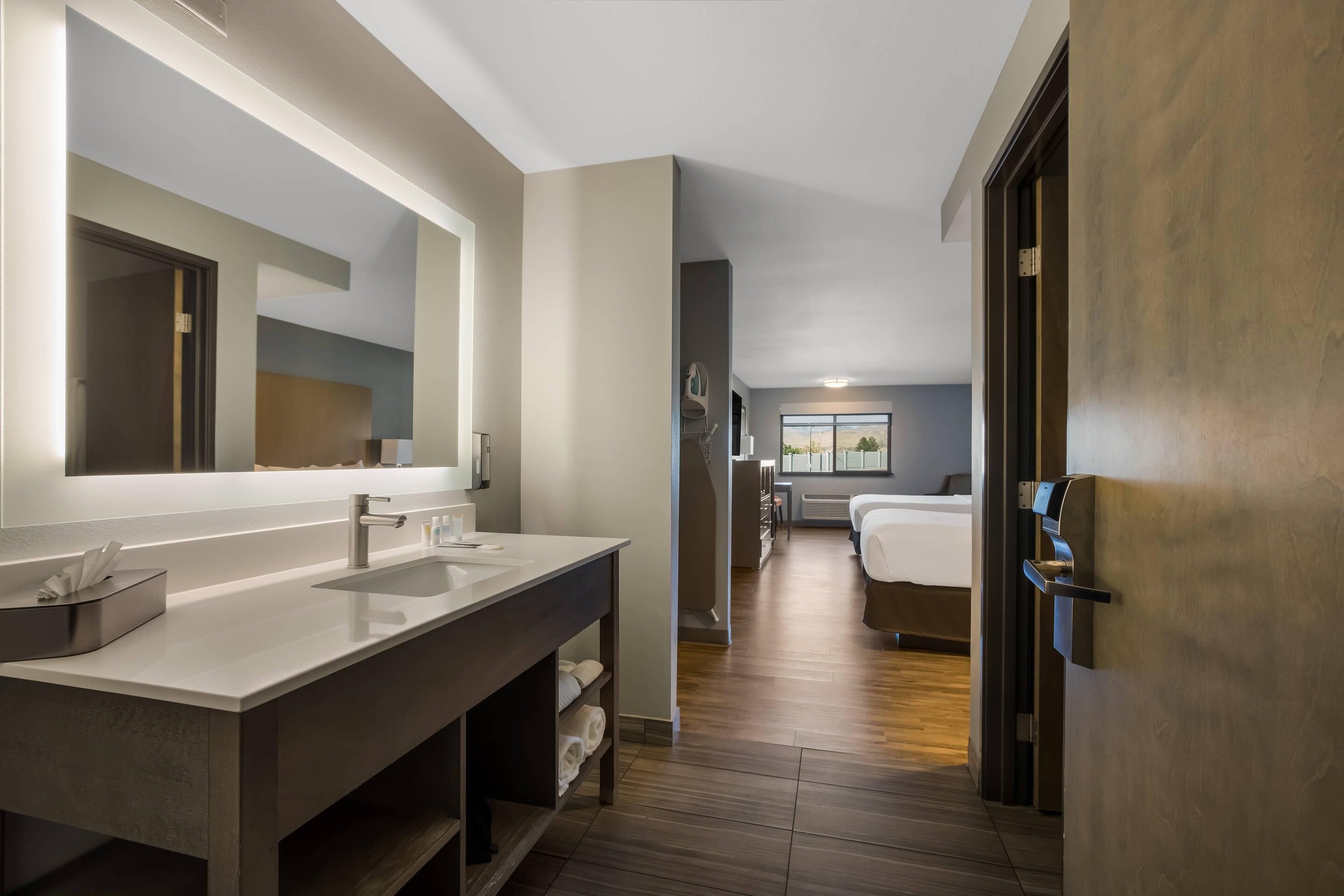 A modern bathroom with a large mirror, dual sinks, and a walk-in shower.