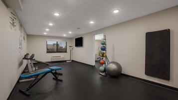 Una palestra con attrezzature per esercizi, uno specchio e una lavagna a parete.