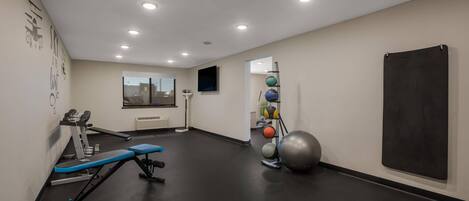 A gym with exercise equipment, a mirror, and a blackboard on the wall.