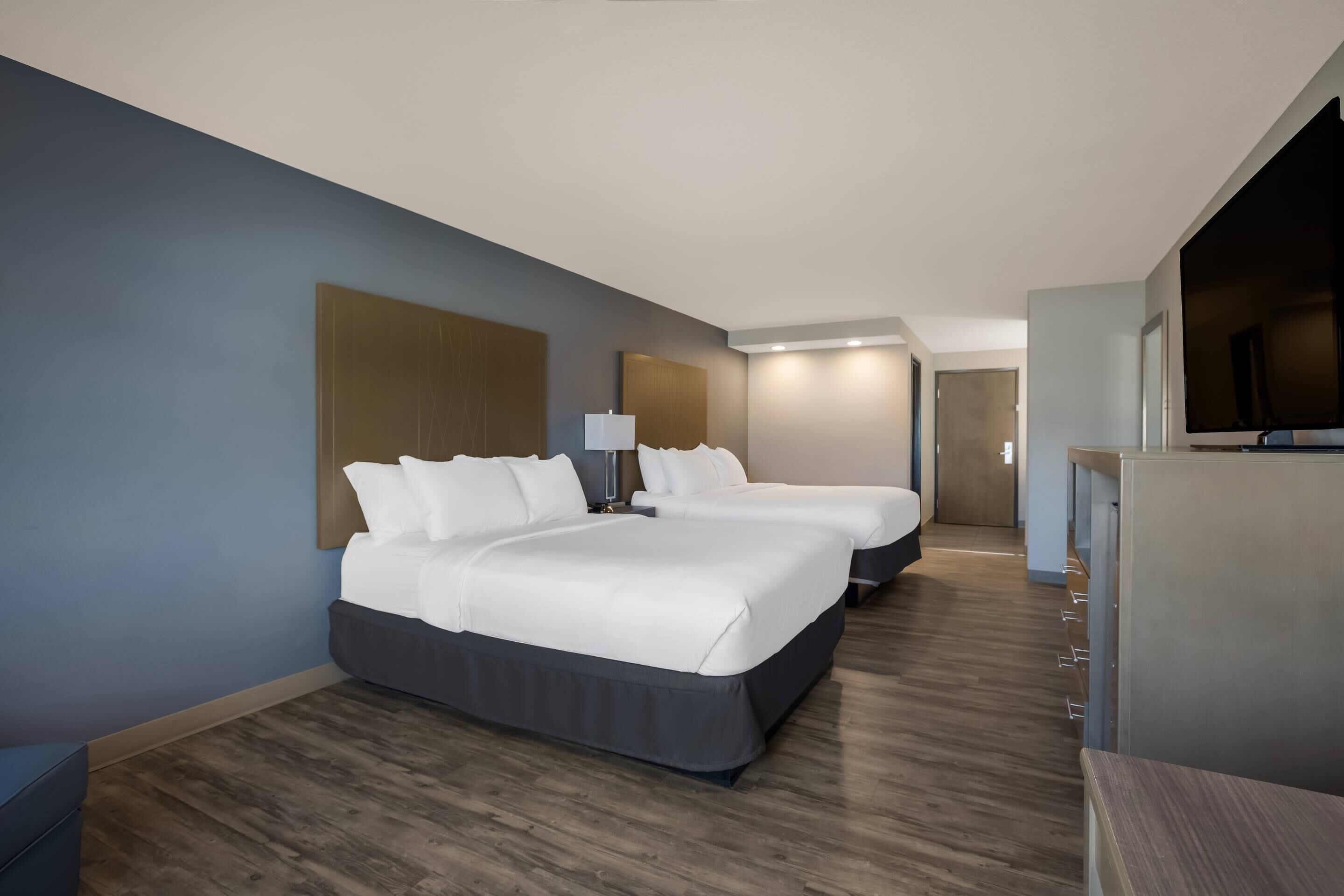 A modern hotel room with a large bed, a desk, and a television.