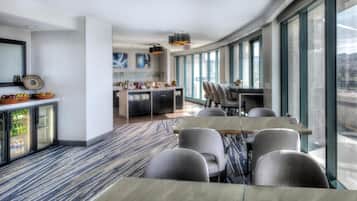 Una habitación de hotel moderna con comedor, ventanas amplias y vistas al exterior.