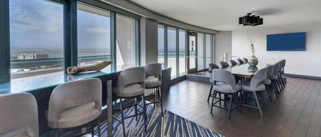 A modern conference room with large windows, a panoramic view of the sea, and a contemporary chandelier.