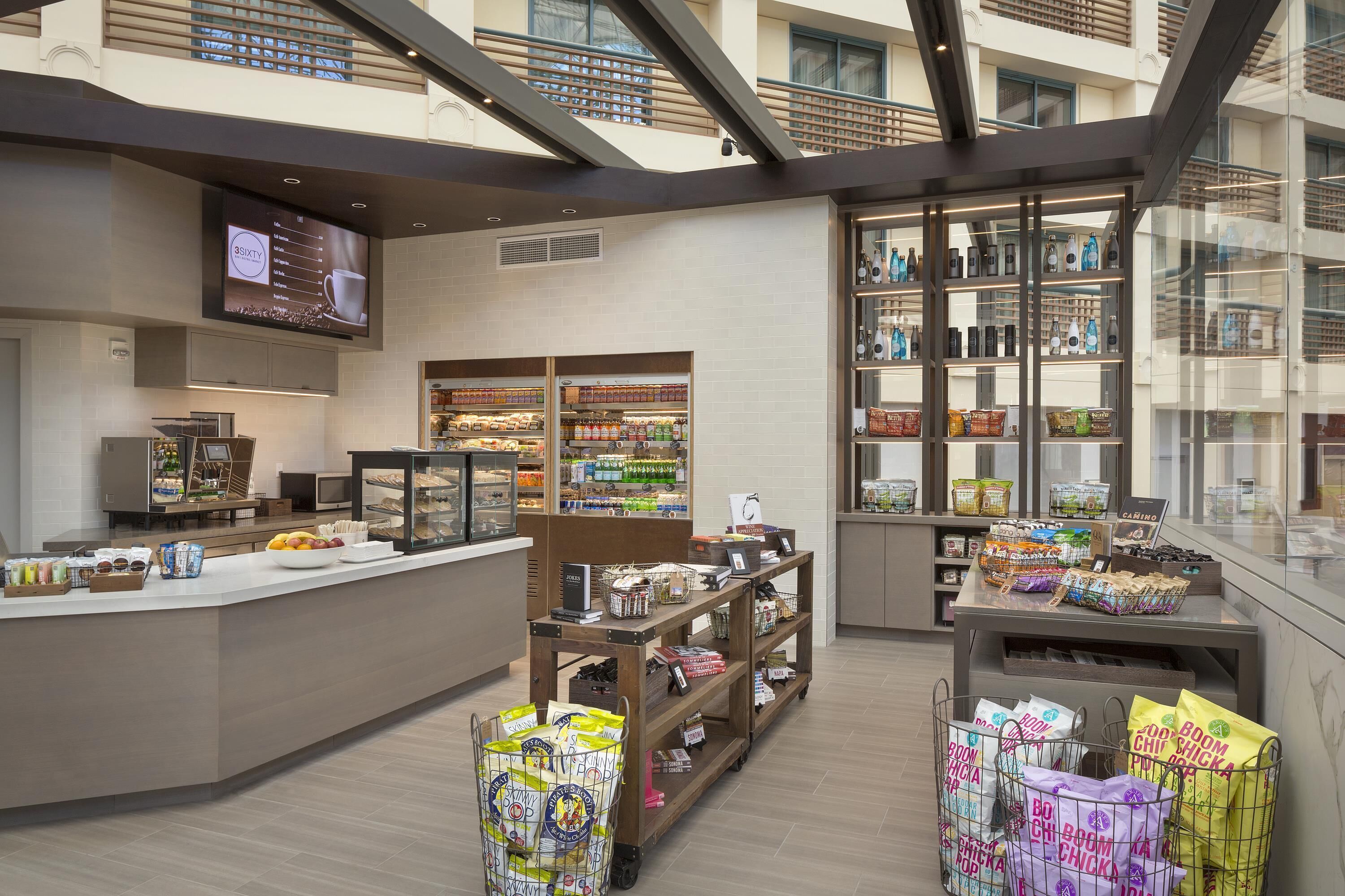 A modern food service area with a self-service counter, refrigerated display cases, and a variety of packaged goods.