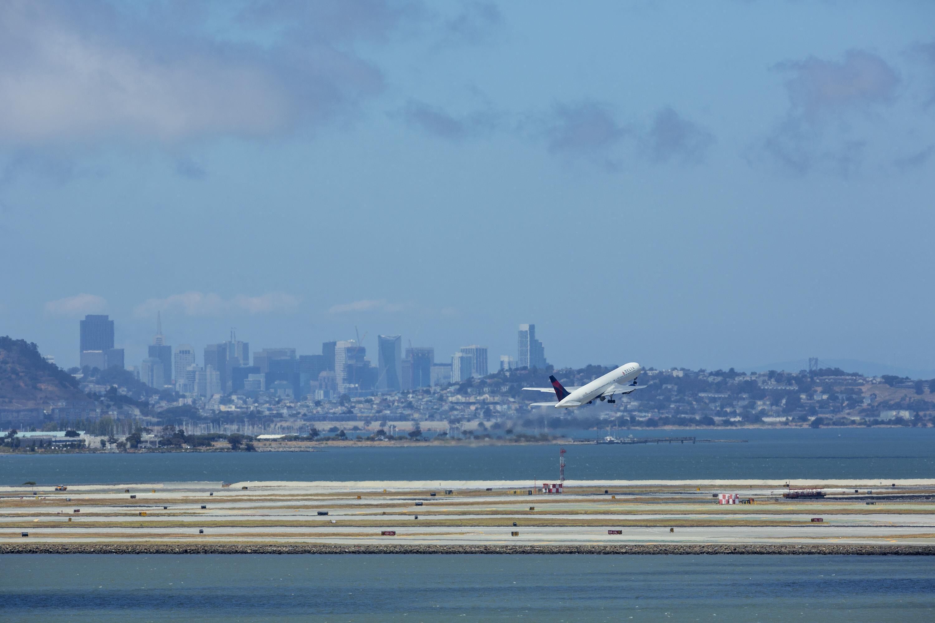 An airplane landing on a runway with a city skyline in the background.