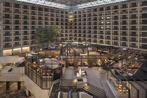 A multi-level hotel atrium with a central open space, multiple seating areas, and a glass ceiling. - Hyatt Regency San Francisco Airport (Burlingame)