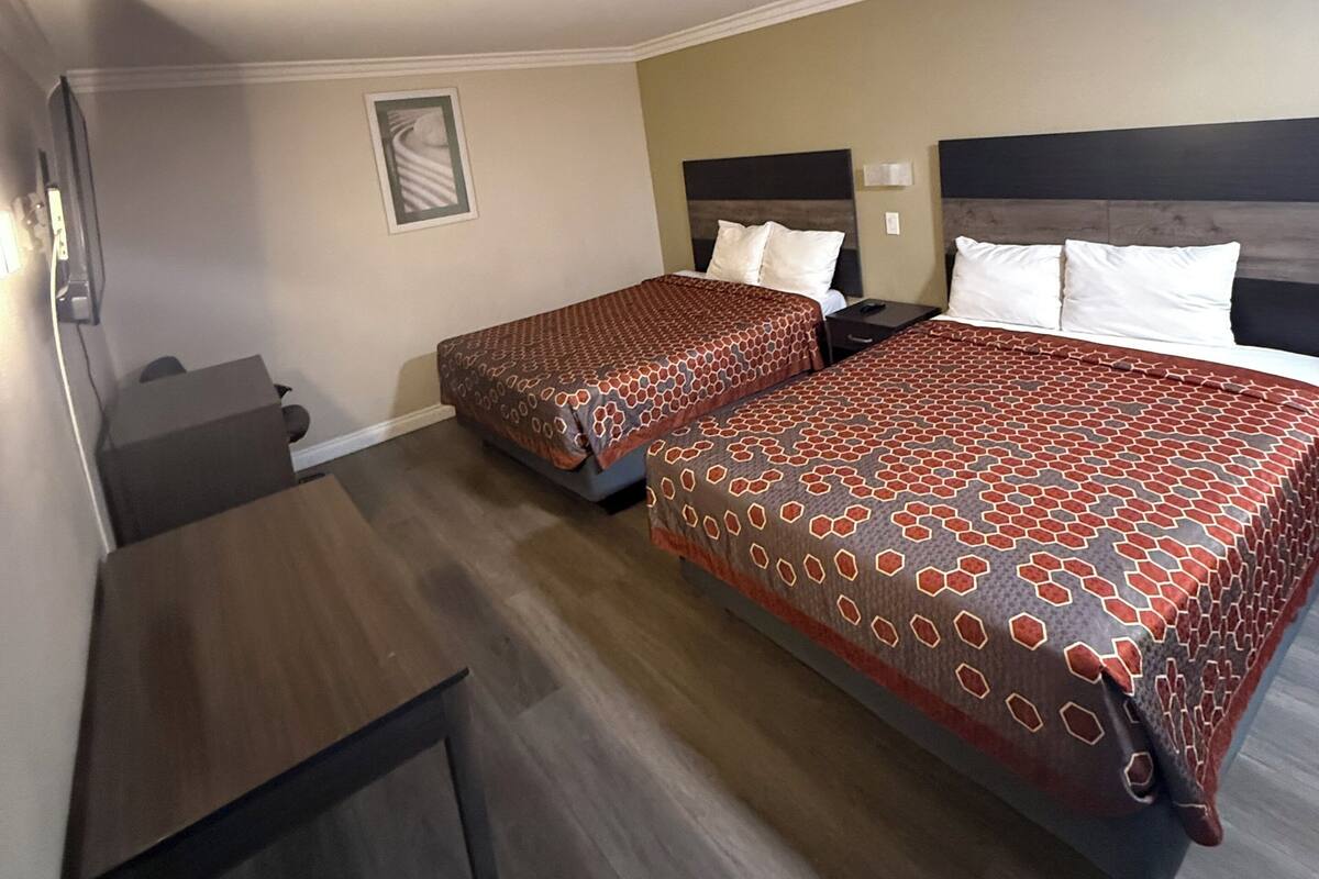 A hotel room with two beds, a desk, and a chair.
