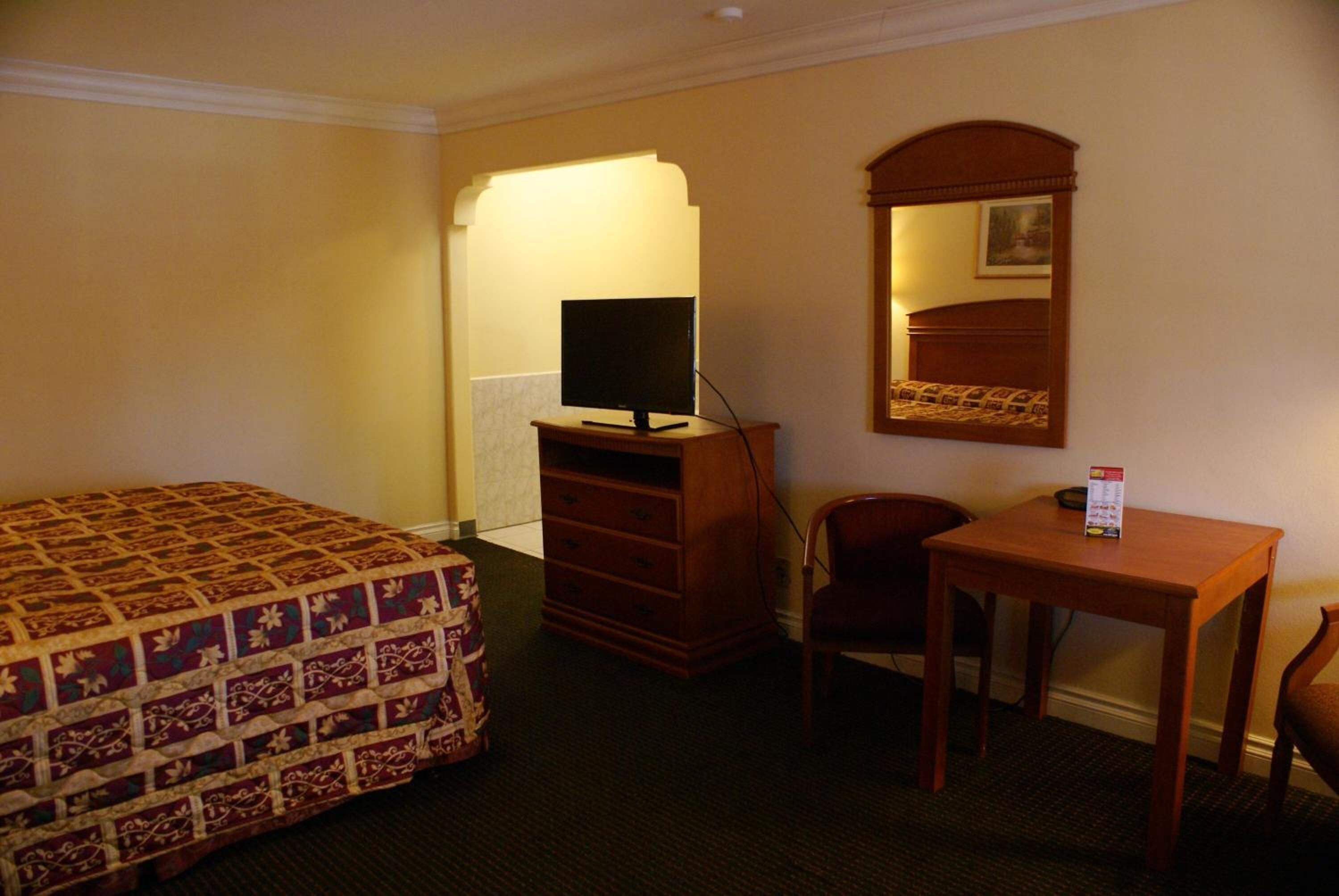 A hotel room with a bed, a dresser, a desk, and a chair.