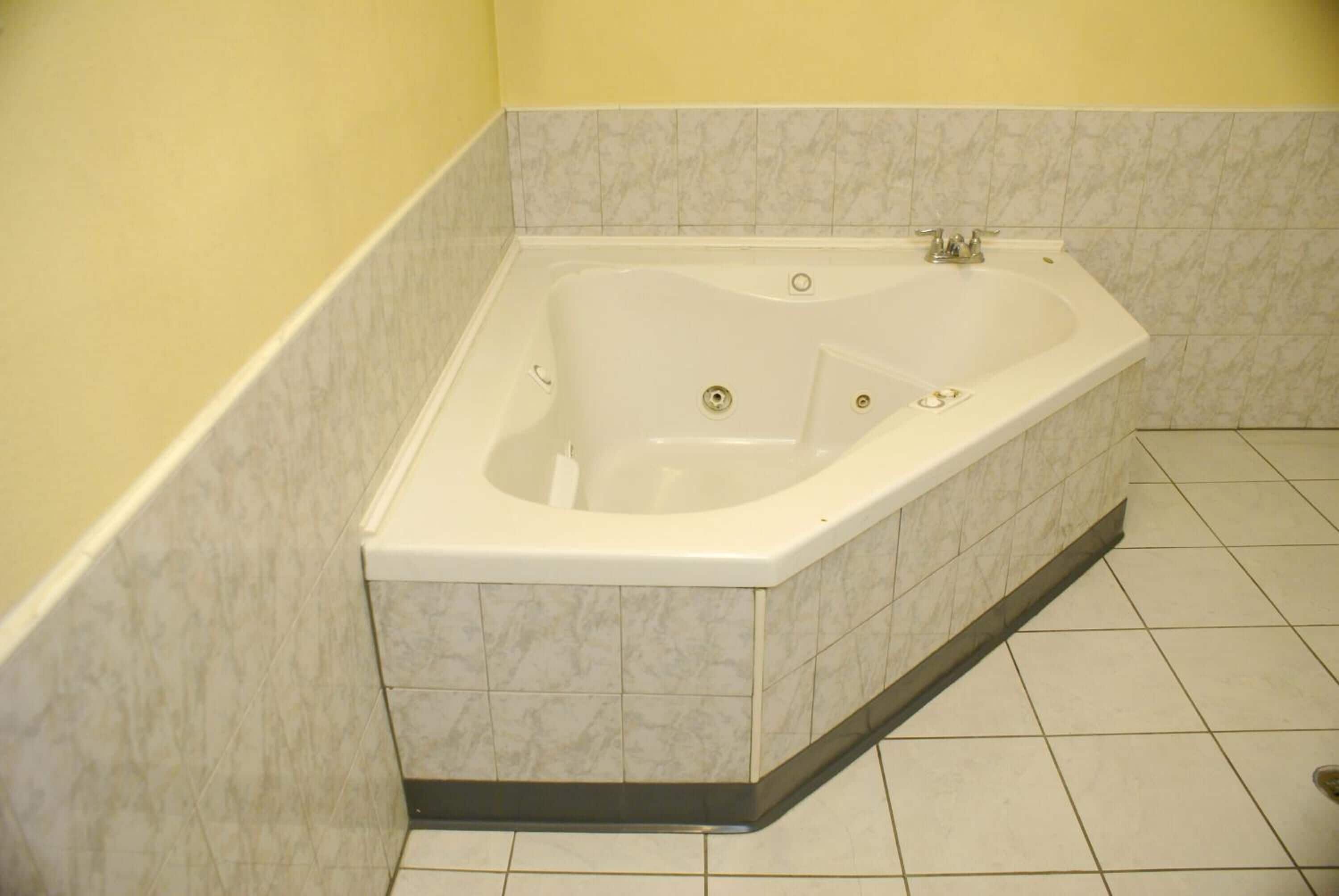 A bathroom with a freestanding bathtub, tiled walls, and a tiled floor.