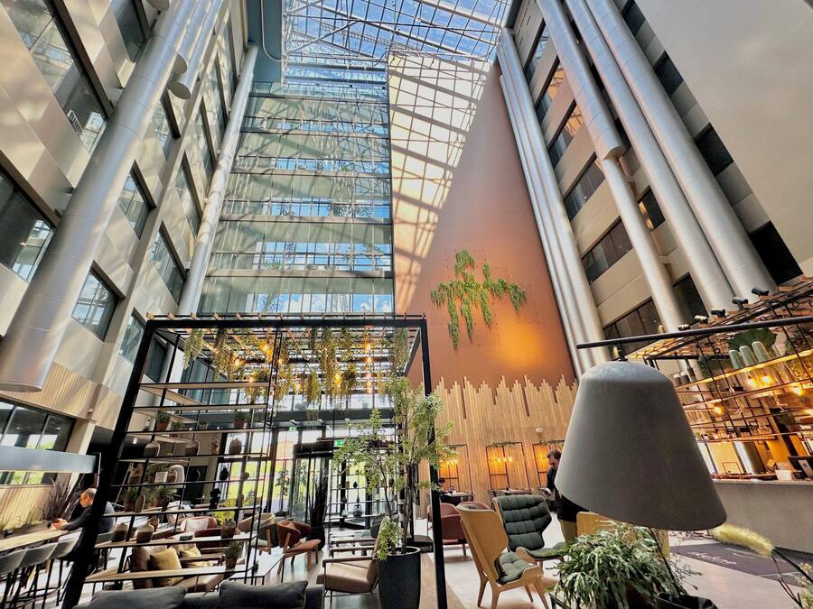 A modern atrium with high ceilings, glass walls, and a variety of seating areas.
