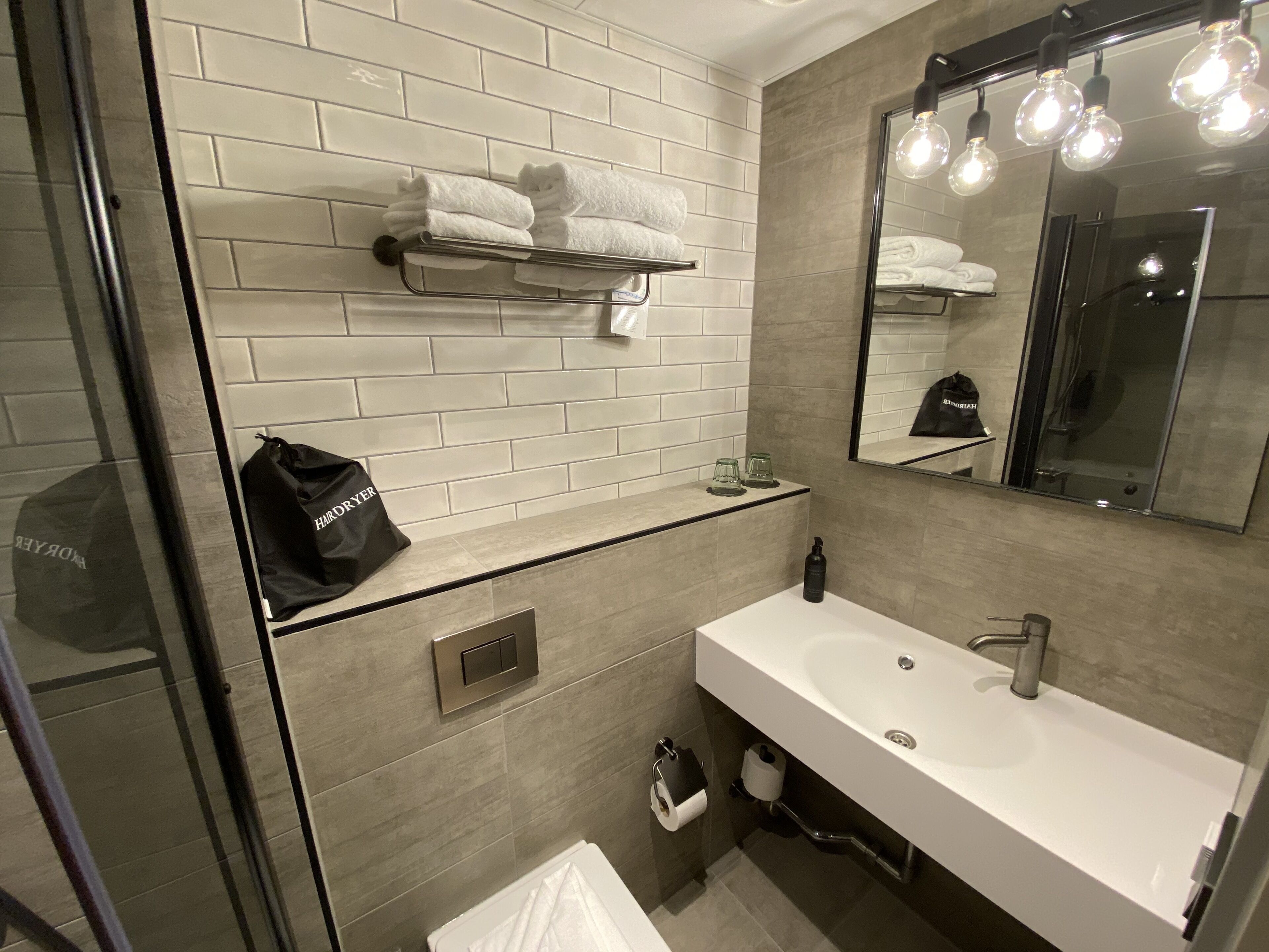A modern bathroom with a white sink, a mirror, and a towel rack.