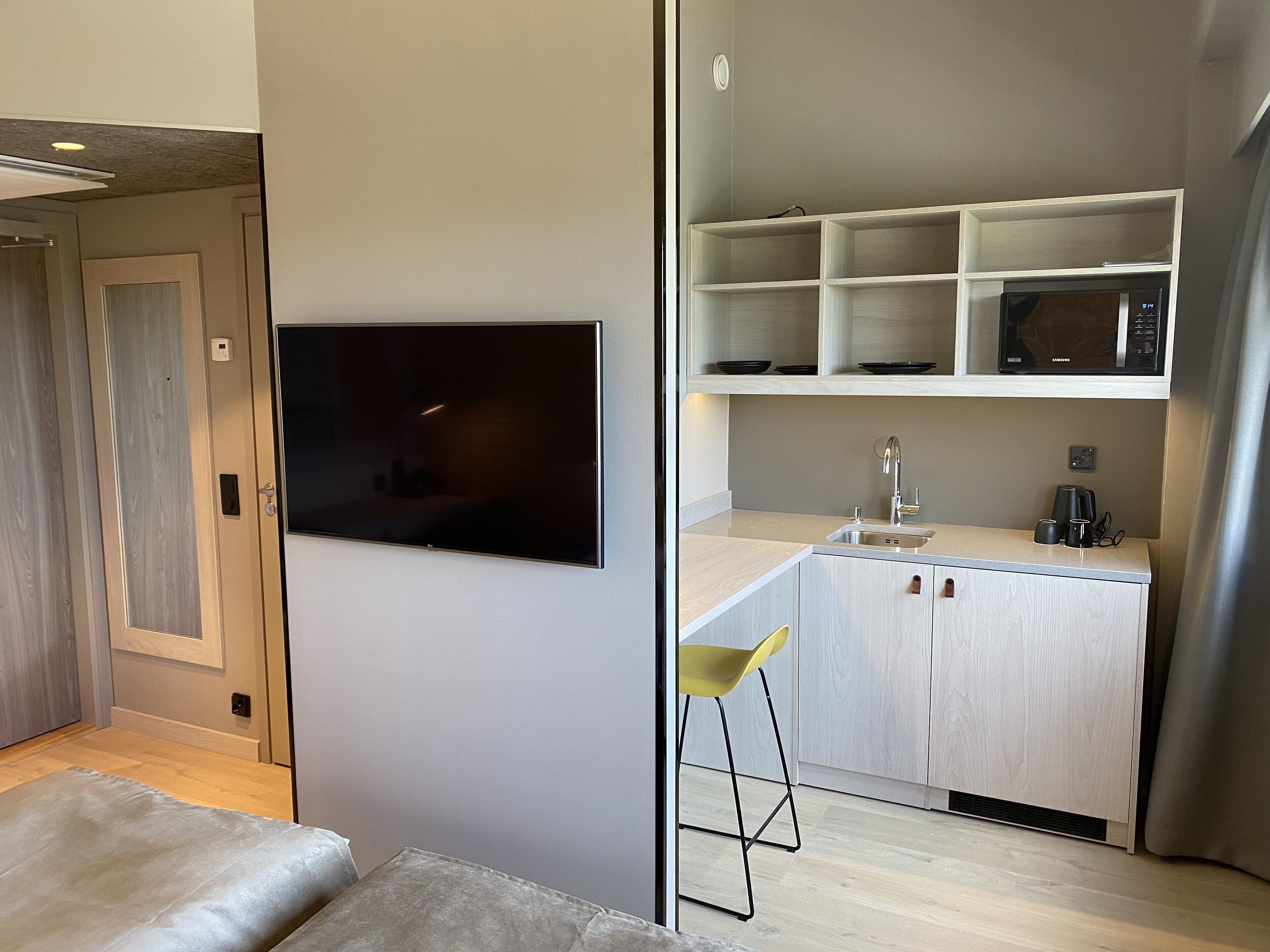 Una kitchenette moderna con microondas integrado, un lavamanos y una pequeña zona de bar.
