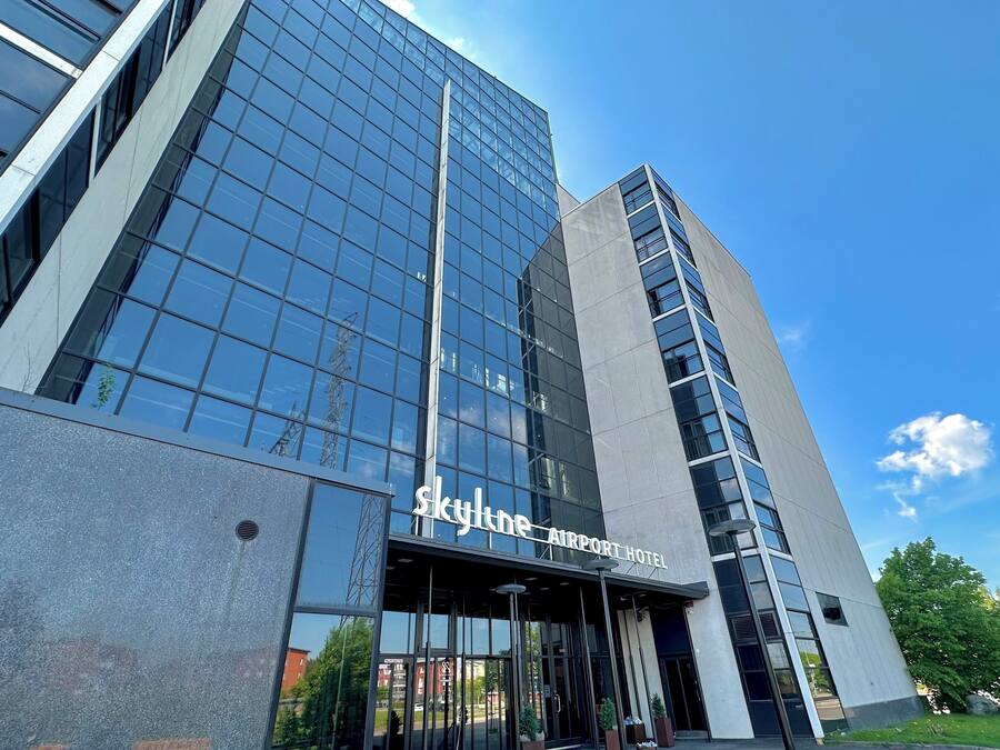 A modern hotel with a glass facade and a sign reading "Skyline Airport Hotel".